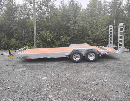 Flatbed trailer on a gravel surface with trees in the background