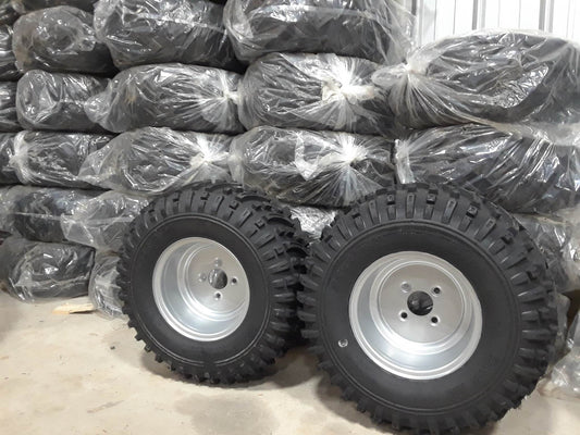 Two tires with rims in front of a stack of wrapped tires from the Trailer Kit.