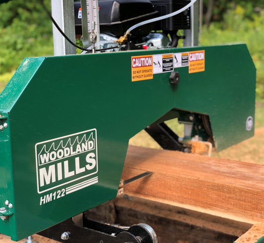 Wooden log being processed by a Woodland Mills HM22 wood splitter in an outdoor setting.