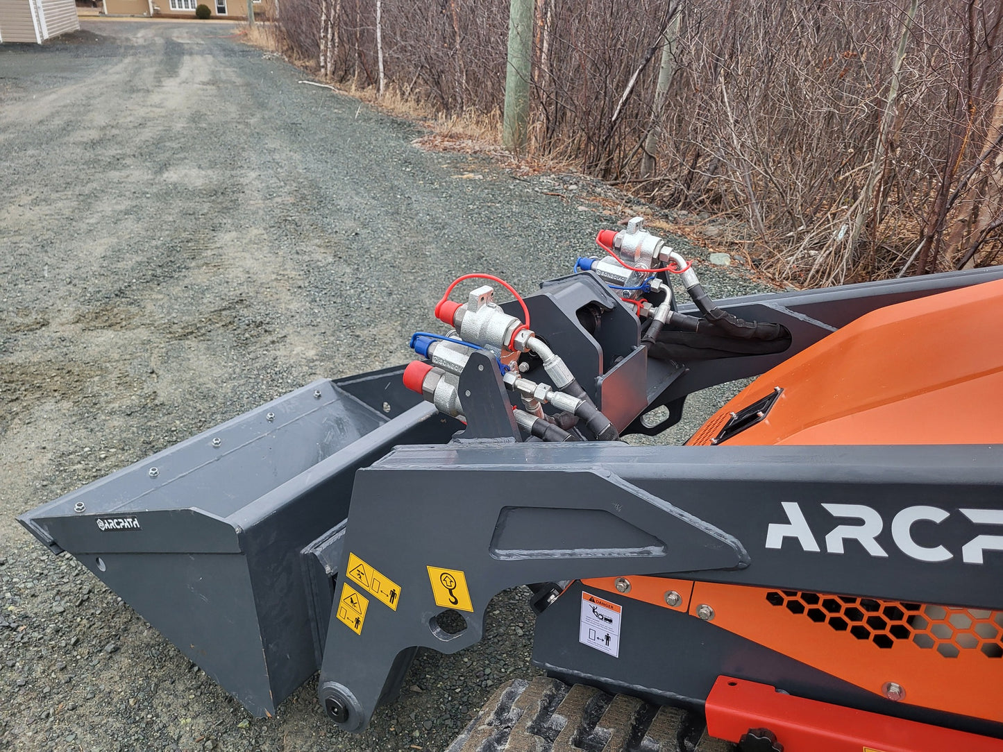 Hydraulic connections and bucket closeup of ATL 1000 Mini Track Loader by ArcPath.