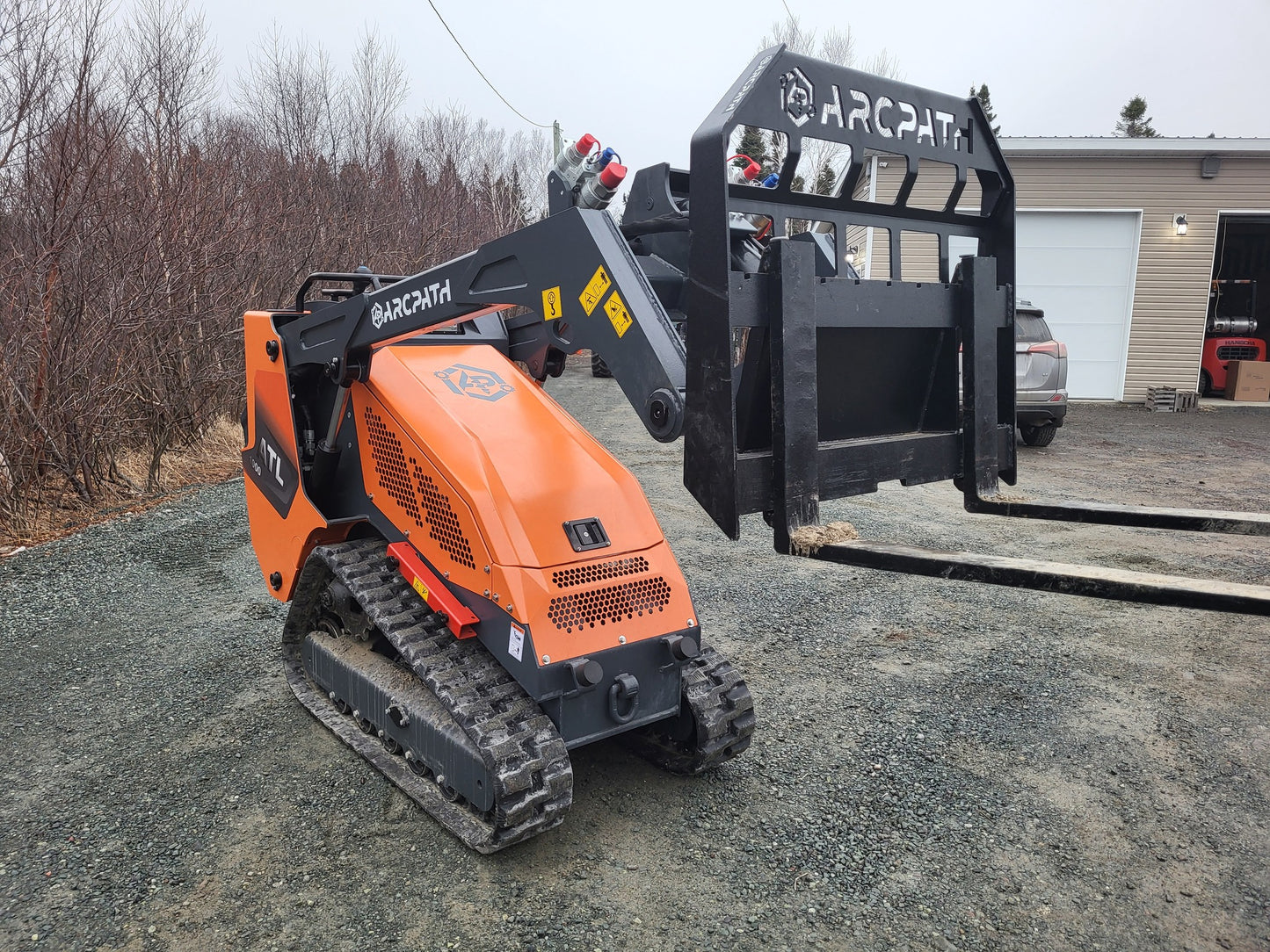 Side view of ATL 1000 Mini Track Loader equipped with forks attachment.