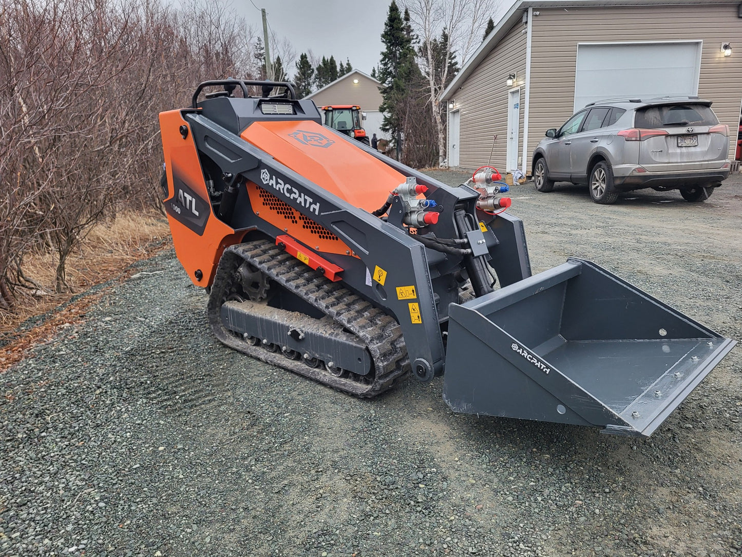 Front angle of ATL 1000 Mini Track Loader with bucket attachment by ArcPath.