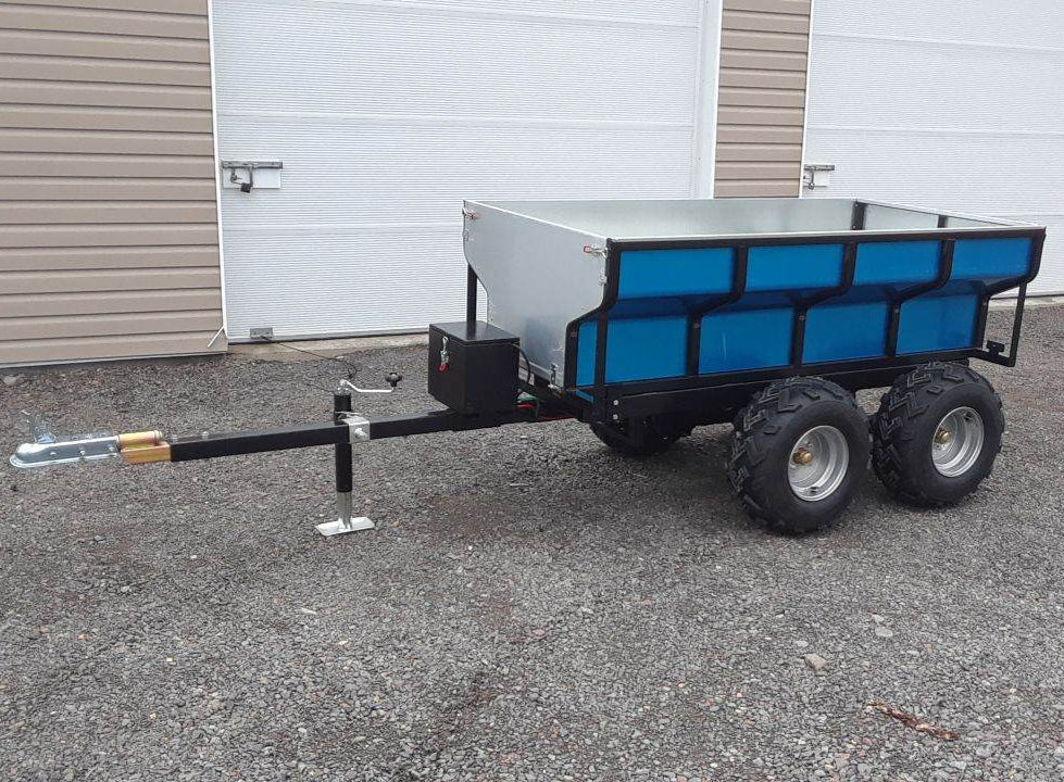ATV Hydraulic Dump Trailer with a blue cargo area parked on a concrete surface.