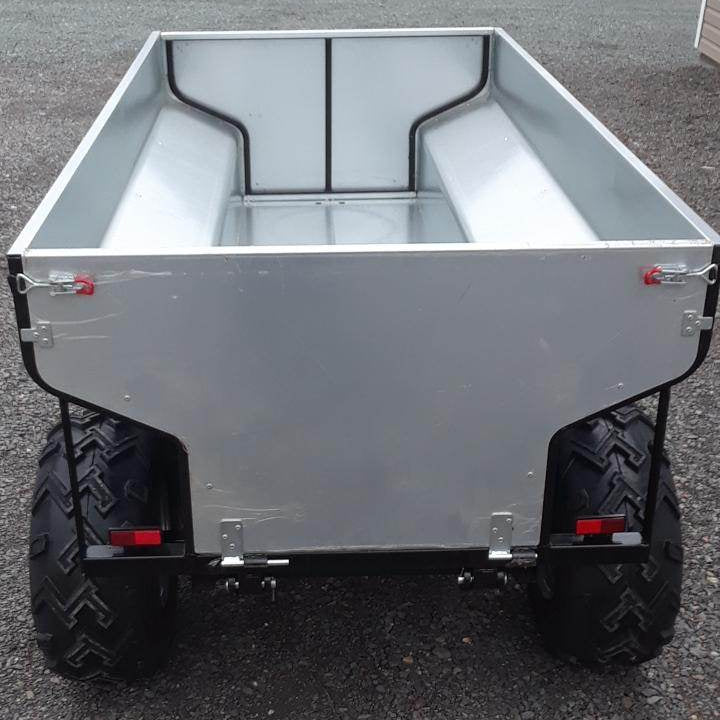 ATV Hydraulic Dump Trailer on a gravel surface with trees in the background