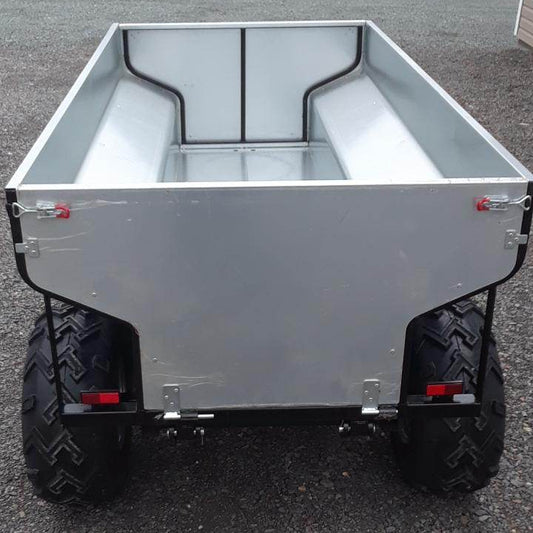 ATV Hydraulic Dump Trailer on a gravel surface with trees in the background