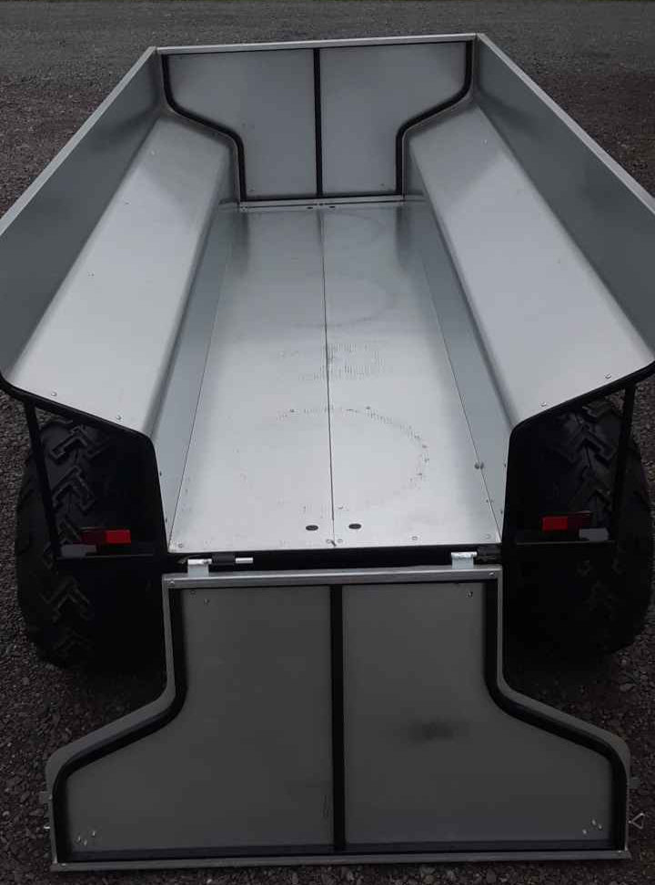 ATV Hydraulic Dump Trailer on a dark surface with a blurred natural background