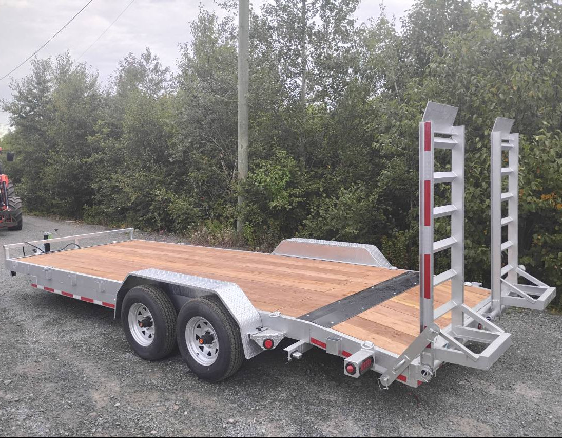 Wooden flatbed trailer with metal frame on a gravel road with trees in the background
