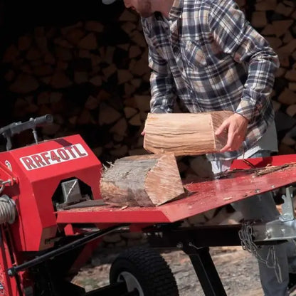 Person using a red RRF40TL – 40 Tons Kinetic Log Splitter with stacked logs in the background