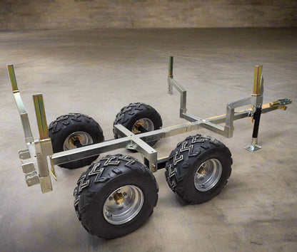 Side view of ATV/UTV logging trailer with walking beam suspension, rugged tires, and a galvanized steel frame for hauling logs.