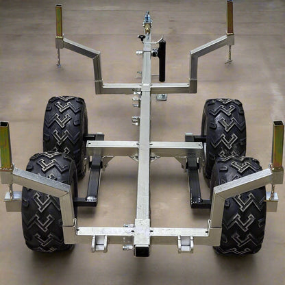 Heavy-duty ATV/UTV walking beam logging trailer with a galvanized frame, tandem wheels, and removable bunks for efficient log hauling.