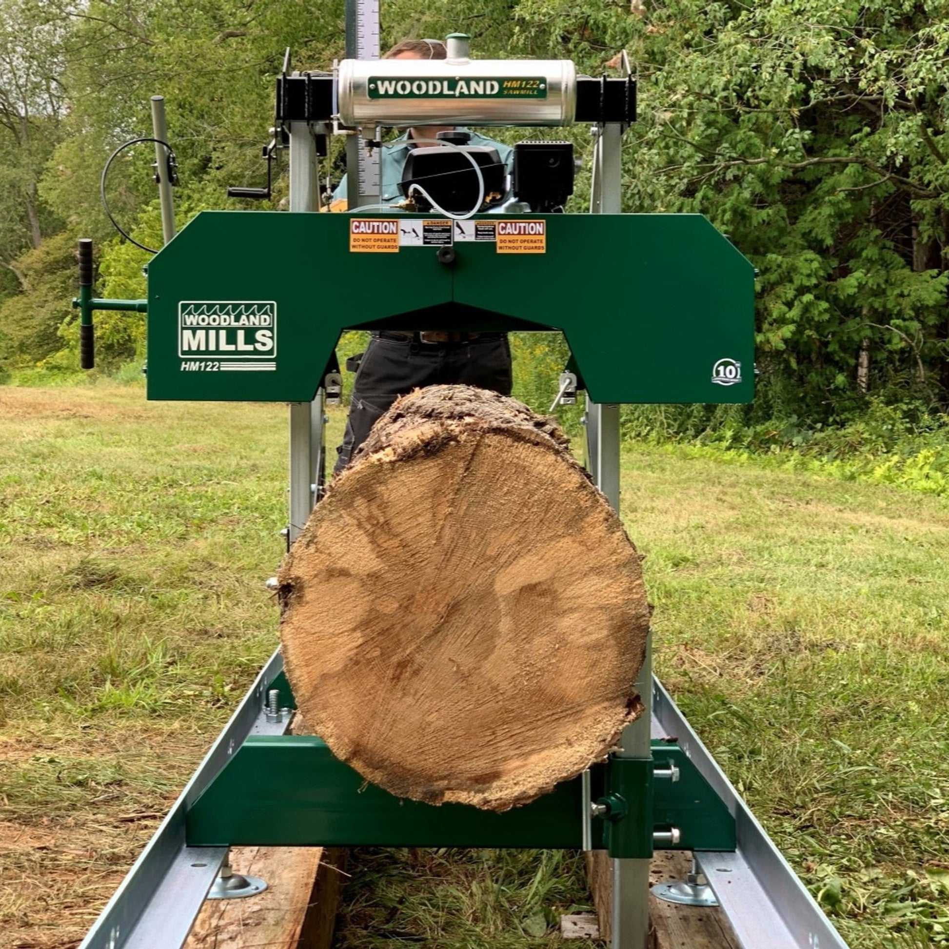 Woodworking Woodland HM122 Portable Sawmill with a log on a grassy outdoor area