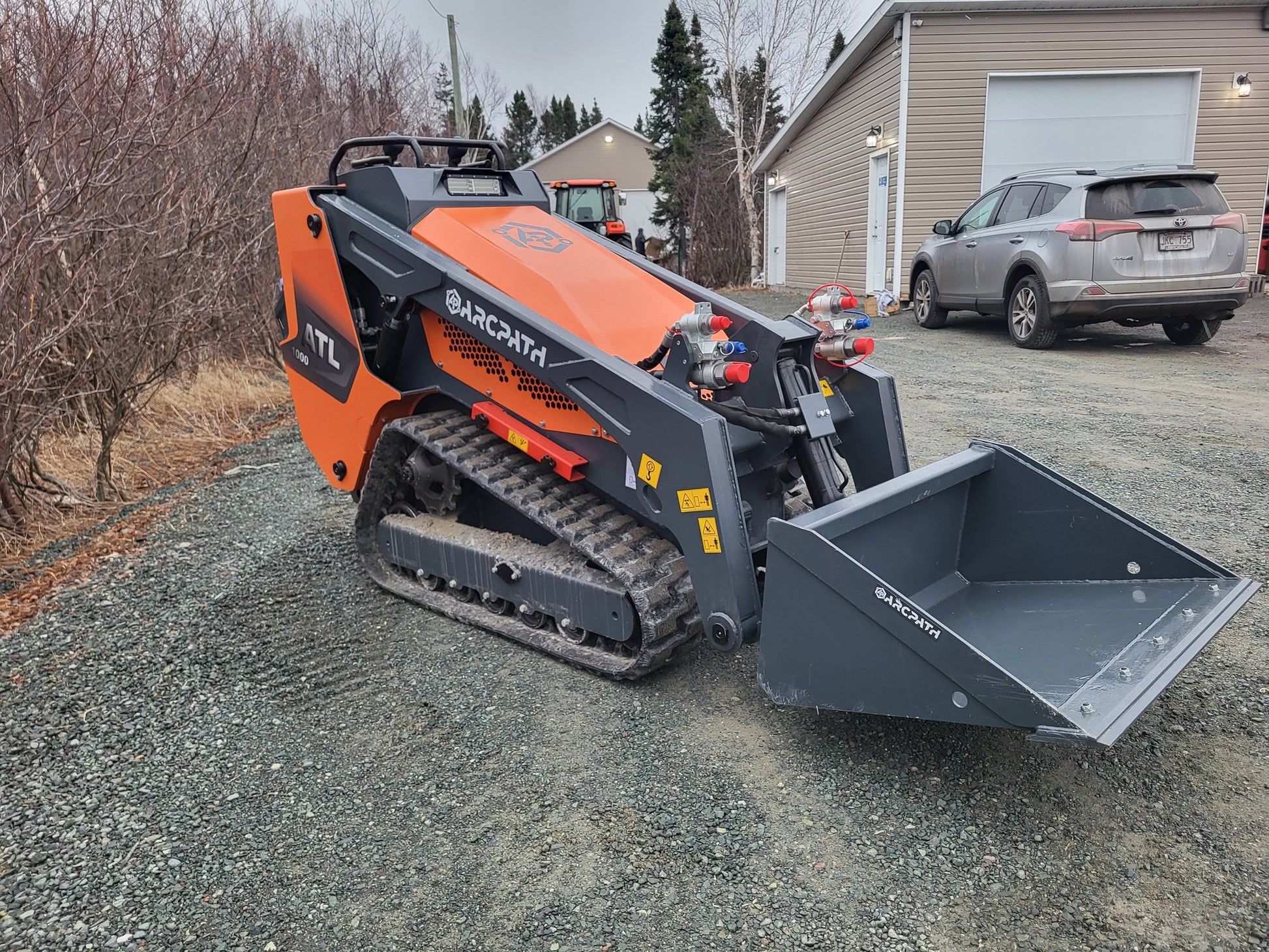 Front angle of ATL 1000 Mini Track Loader with bucket attachment by ArcPath.